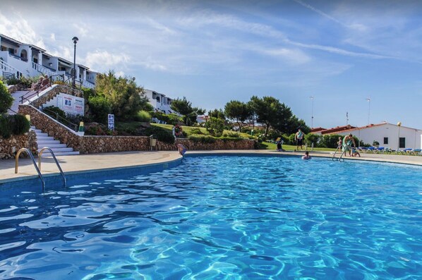Une piscine à l’eau d’un bleu limpide, entourée d’escaliers en pierre et de verdure.