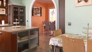 Une cuisine comprenant un coin repas, avec une table et des chaises, un meuble et un plan de travail.