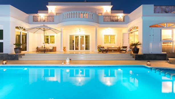 Une maison moderne dotée d’une piscine, de grandes fenêtres et d’un espace salon extérieur.