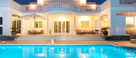 Una casa moderna con piscina, ventanas amplias y mobiliario de exterior.