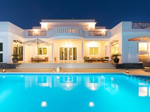 A modern house with a swimming pool, large windows, and outdoor seating. - COSTA GOLF VILLA IN COSTA TEGUISE (Teguise)