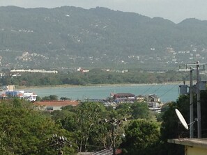 A coastal town with buildings near the water, surrounded by hills. - City Studios at Upper Deck (Montego Bay)