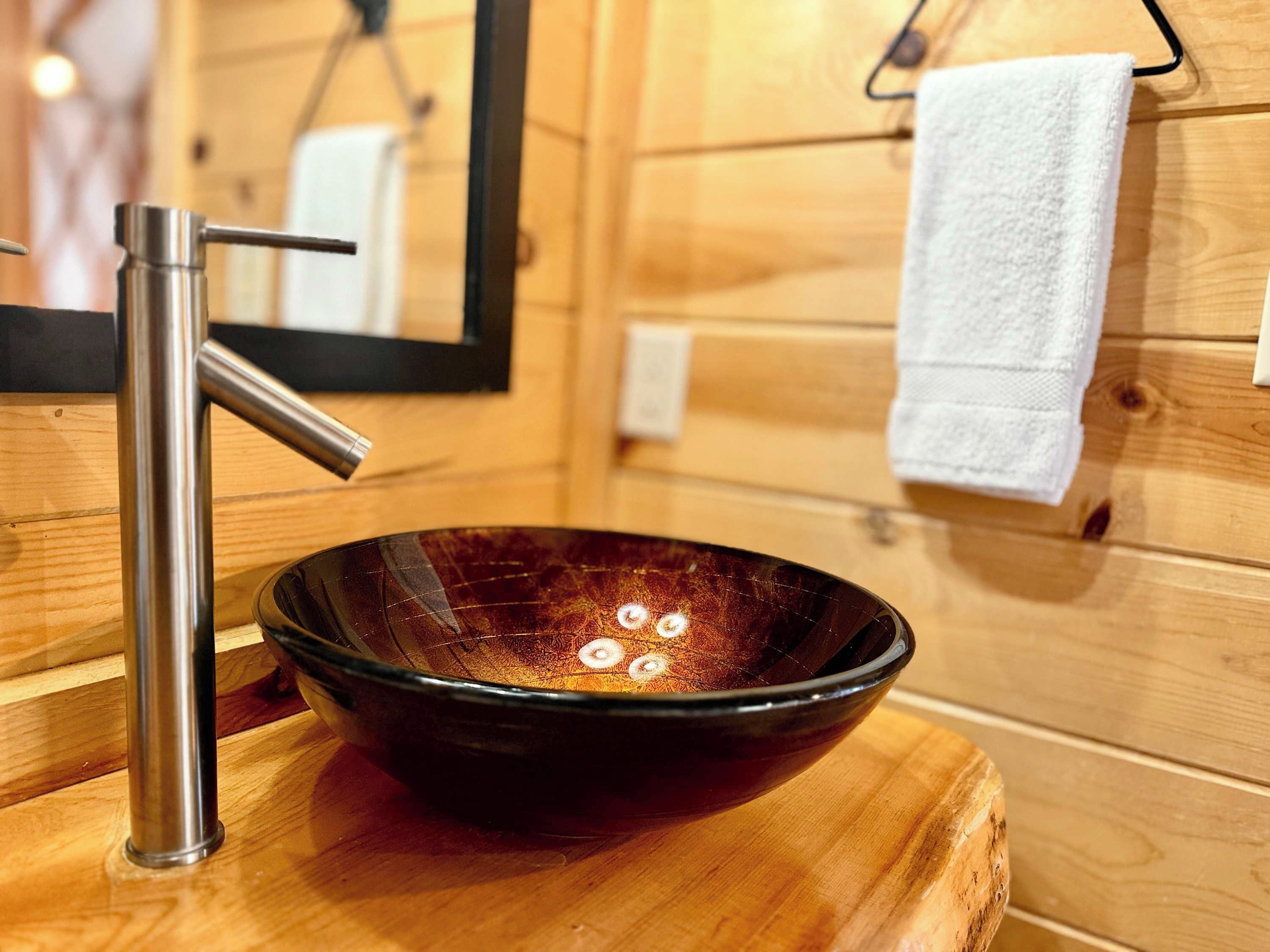 A wooden interior with a modern bathroom sink, a mirror, and a towel rack.