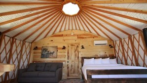 Een knus interieur met een houten plafond, een bed, een bank en een deur.