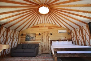 Un interno accogliente con soffitto in legno, un letto, una poltrona e una porta.