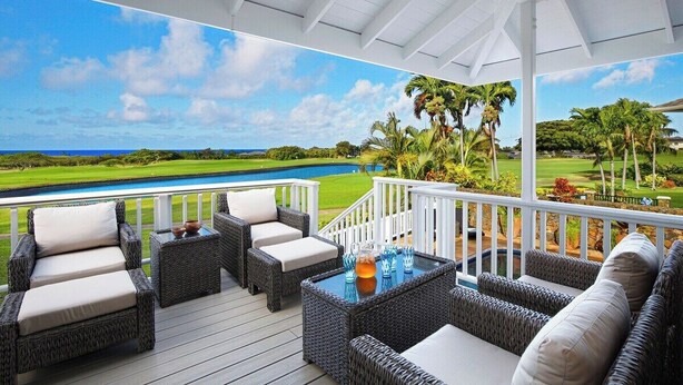 Una terrazza esterna coperta con mobili in vimini e vista su un campo da golf e l'oceano.