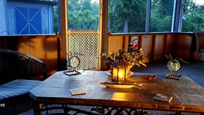 Una mesa de madera con un reloj, un farol y una pequeña planta en maceta.