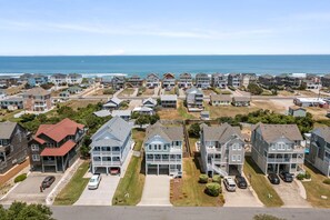 A coastal residential area with multiple two-story houses, some with balconies, and a clear view of the ocean. - Kimberly's Kottage: Oceanside, Private Pool (Nags Head)