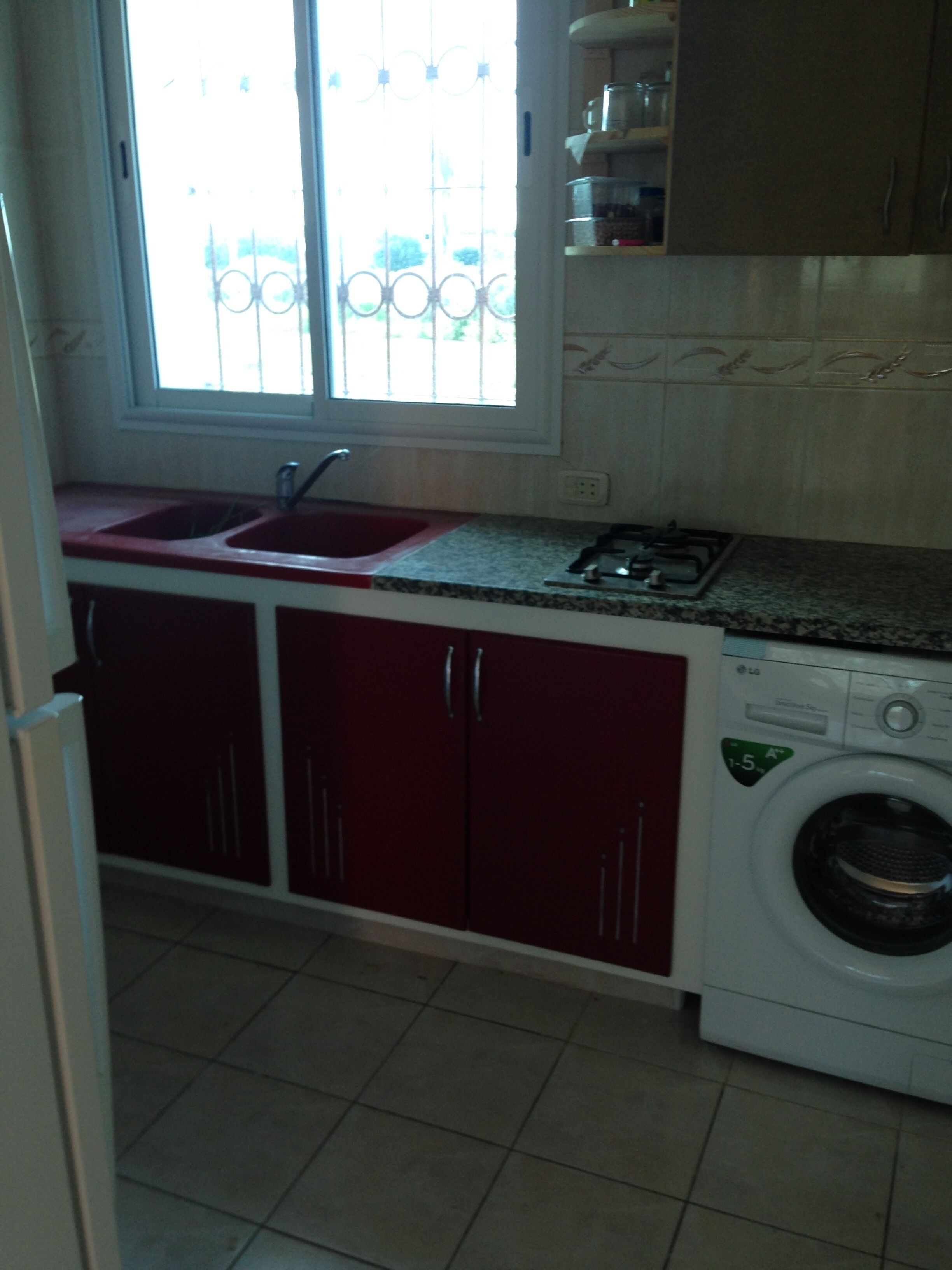 Una cocina con un lavabo, armarios, una estufa y una lavadora.