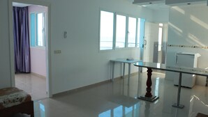 Um quarto de hotel espaçoso com uma cama grande, uma mesa pequena e uma janela com cortinas.