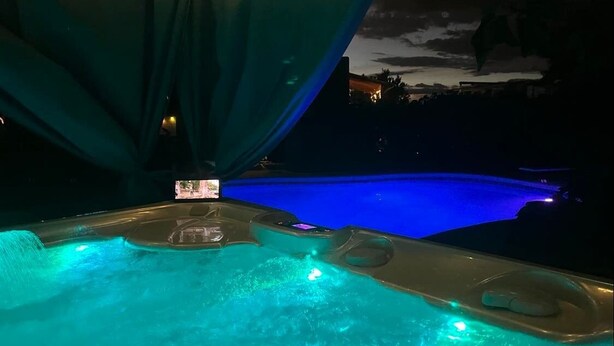 Un jacuzzi con vista a una piscina y un edificio al fondo.