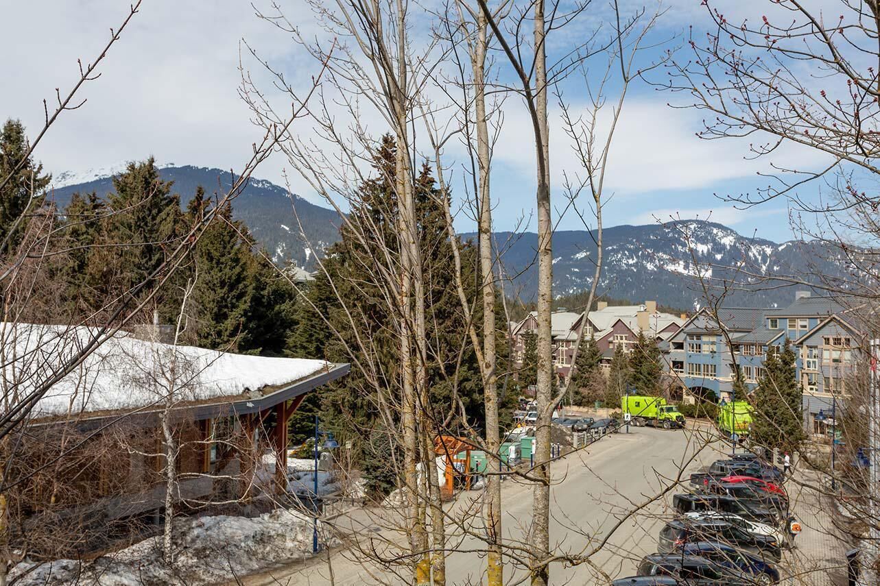 A view of a mountain town with buildings, a parking lot, and a snow-covered roof.