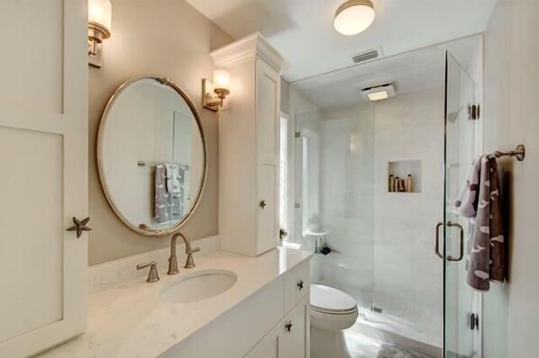 A modern bathroom with a round mirror, a sink, and a glass-enclosed shower.