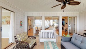 A sunlit room with a ceiling fan, a striped sofa, a grey couch, and a wicker table. - Direct Ocean Front, Private Pool, 100 steps to Lighthouse (St Simons Island)