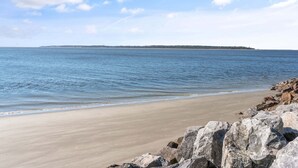 A beach with a rocky shoreline and a distant landmass. - Direct Ocean Front, Private Pool, 100 steps to Lighthouse (St Simons Island)