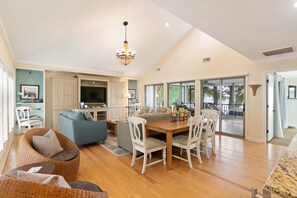 A spacious living area with a dining table, chairs, a sofa, and a chandelier.