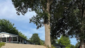 A wooden dock leading to a small water body, a concrete retaining wall, and a building with a porch and American flag.