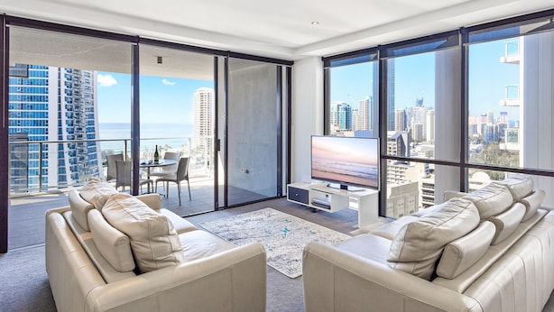 A spacious living room with a large TV, comfortable seating, and a balcony with a city view. - Circle on Cavill Ocean View (Surfers Paradise)