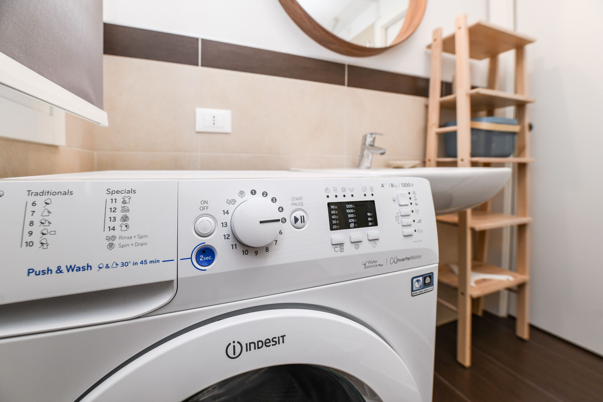 A front-loading Indesit washing machine with a control panel, a push and wash button, and a timer.