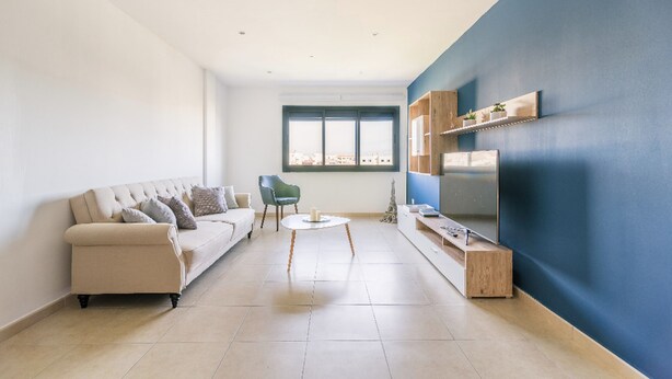 Ein Wohnzimmer mit Sofa, Sessel, Couchtisch und Fernseher auf einem Schrank.