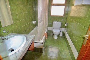 A bathroom with green tiled walls, a white sink, a bathtub, and a toilet. - Comfortable Apartment in Puerto Rico (Mogán)