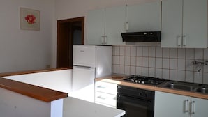 Uma cozinha com geladeira branca, fogão e armários claros.