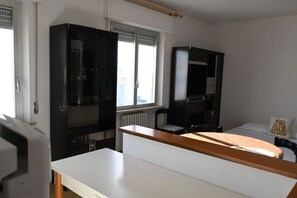 Una stanza con un letto, una scrivania, due armadietti neri e una finestra.
