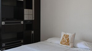 Quarto com cama, guarda-roupa e travesseiro com texto.