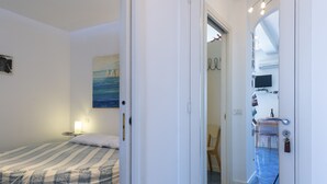 Un dormitorio con una cama, una lámpara de noche y un cuadro en la pared.