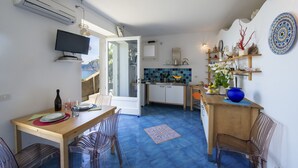 Cocina compacta con zona de comedor, televisor montado en la pared y vistas a través de la puerta abierta.