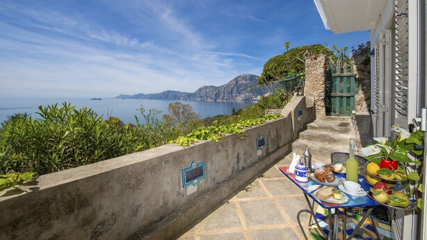 Una terraza con mesa dispuesta para el desayuno y vistas panorámicas de la costa.