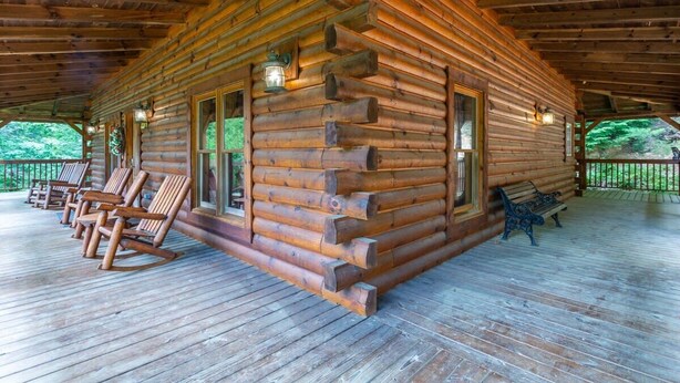 Una baita di legno con portico, poltrone a dondolo e una panca.