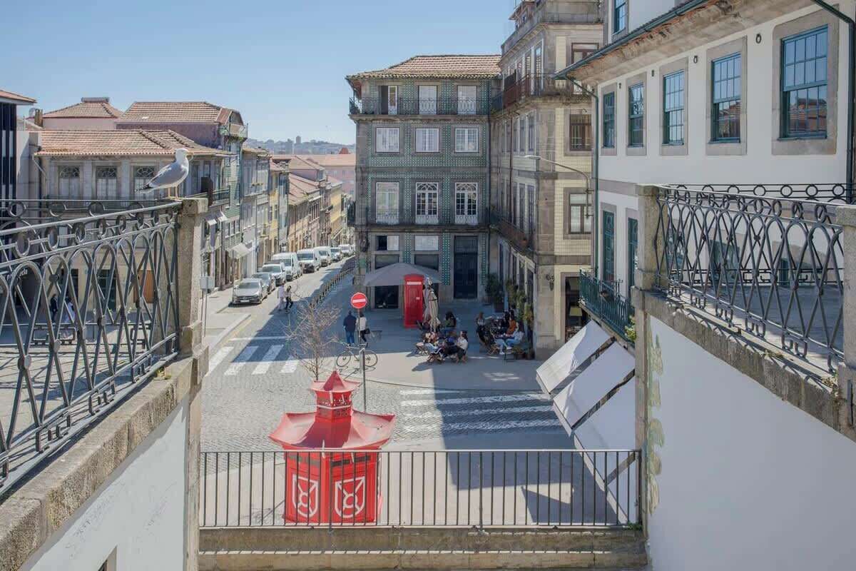 A street view with buildings, a red kiosk, and a pedestrian crossing.