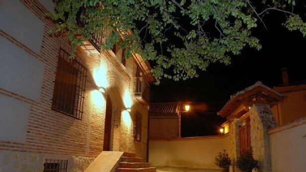 A courtyard with a brick building, a staircase leading to a door, and a small garden area with potted plants.