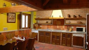 A traditional kitchen with wooden cabinets, a brick backsplash, and a dining area with a wooden table and chairs.
