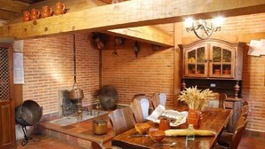 A rustic dining area with a wooden table, chairs, and a brick wall.