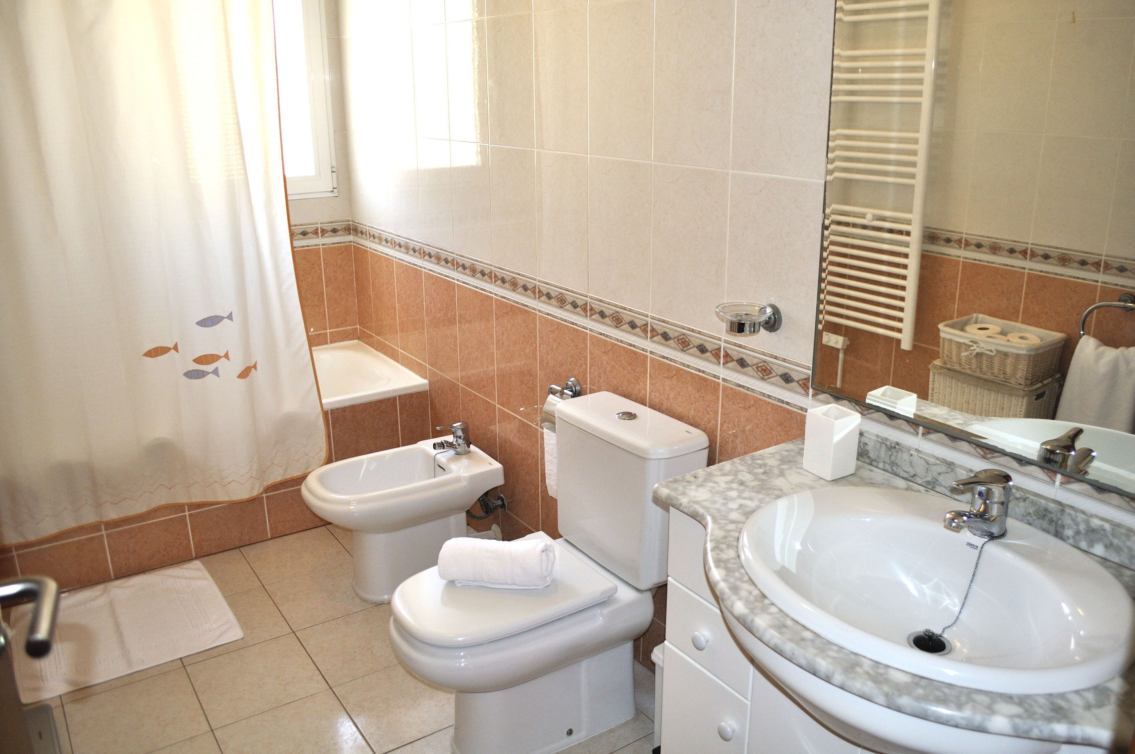 Un baño con inodoro, bidé y lavamanos.