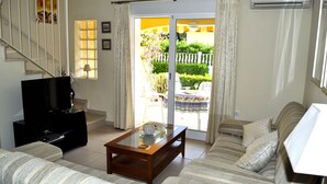 A living room with a sofa, a coffee table, a TV, and a sliding glass door leading to a garden. - aldeamar, bungalow - 2 bedrooms in quiet urbanization. (Els Poblets)