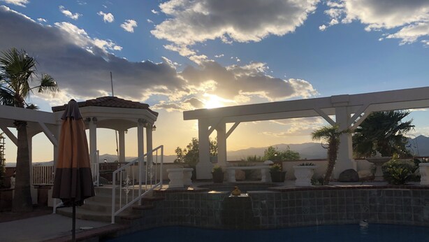 Un espace piscine agrémenté d’une pergola, d’un belvédère et offrant une vue sur les montagnes en arrière-plan.