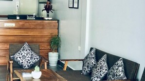 A modern living room with a wooden coffee table, two armchairs, a sofa, and a small potted plant. - Maison Rivera Guest House (Kampot)