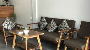 A modern living room with a sofa, two armchairs, a coffee table, and a small potted plant. - Maison Rivera Guest House (Kampot)