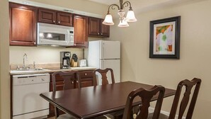 Une cuisine compacte dotée de meubles en bois, d’un four à micro-ondes, d’un réfrigérateur, d’un lave-vaisselle et d’une table à manger avec des chaises.