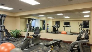 Une salle de sport équipée de machines de cardio, de bancs de musculation et de ballons d’exercice.