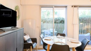 Un espace repas moderne avec une table ronde pour quatre personnes, un canapé et un téléviseur posé sur un meuble.