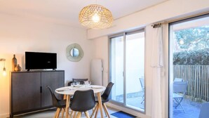 Un espace repas moderne avec une table ronde, des chaises noires et un téléviseur posé sur un meuble.