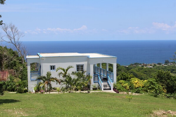 A white building with blue accents, a staircase, and a view of the ocean.