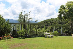 A gazebo with a stone table in a lush garden with mountains in the background. - Panoramic views with room to roam in a relaxing environment. (Haughton Court)