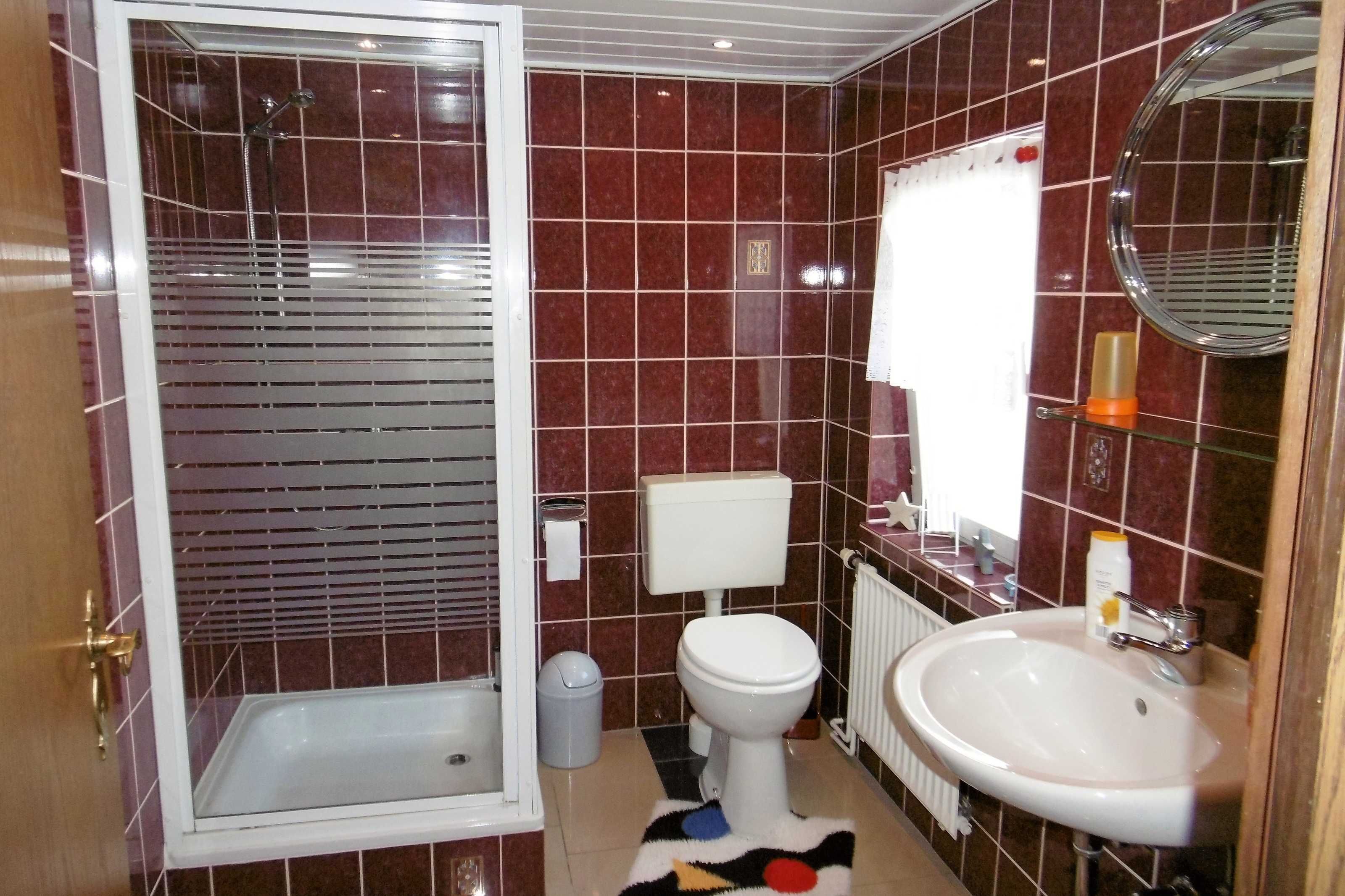 Ein Badezimmer mit Dusche, Toilette, Waschbecken und Spiegel.