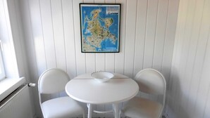 Une petite table blanche avec deux chaises, une carte accrochée au mur et une fenêtre avec un radiateur.