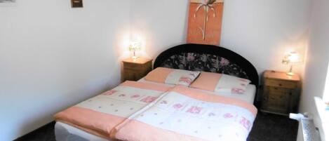 A neatly made bed with a floral bedspread, two bedside lamps, and a wall-mounted artwork.